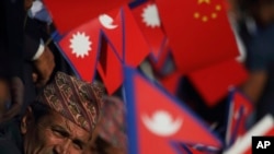 资料照：尼泊尔政府官员手持尼泊尔和中国国旗，在公路旁迎接中国国家主席习近平的到来。（2019年10月12日）