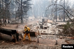 A firefighter extinguishes a hot spot in a neighborhood destroyed by the Camp Fire in Paradise, California, Nov. 13, 2018.
