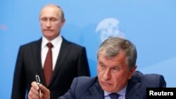 روسی آئل کمپنی روزنیفٹ کے سی ای او ایگور سیچن، سینٹ پیٹربرگ کی ایک تقریب میں شریک ہیں جب کہ روسی صدر ولادی میر پوٹن ان کے پیچھے کھڑے ہیں۔ 24 مئی 2014