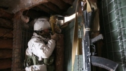 A Ukrainian Military Forces serviceman, watches through a spyglass in a dugout on the frontlines with Russia-backed separatists near Horlivka, Donetsk region, Ukraine, Jan. 23, 2022.