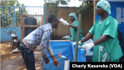 Deux infirmiers à l'entrée d'un centre de traitement de l'épidémie d'Ebola à Beni, 15 octobre 2018. (VOA/Charly kasereka)
