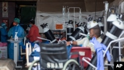 Health worker in a protective suit works in the makeshift emergency unit at Steve Biko Academic Hospital in Pretoria, South Africa, Jan. 11, 2021, which is battling an ever-increasing number of Covid-19 patients.