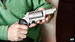 FILE - In this photo taken Feb. 26, 2016, Lance Toland, the owner of Lance Toland Associates, an aviation insurance company with three offices in Georgia, holds a Taurus revolver, in Atlanta.