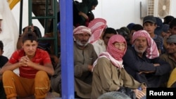 FILE - Syrian refugees wait to board a Jordanian army vehicle after crossing into Jordanian territory with their families, in al-Ruqban border area, near the northeastern Jordanian border with Syria, and Iraq, near the town of Ruwaished, 240 km (149 miles) miles) east of Amman, Sept. 10, 2015. 