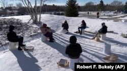 A fourth-grade class uses buckets for seats as they study outside at the Gerald Talbot School, in Portland, Maine on December 8, 2020. (AP Photo/Robert F. Bukaty)