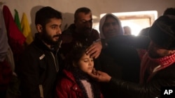 In this Feb. 12, 2020, photo, Malak Saad Dakhel, 11, is anointed by a holy man inside a Yazidi shrine as she is welcomed home by her relatives after her escape from Syria, in Sharia, Iraq.