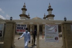 A Muslim man walks past COVID-19 guidelines at the gate of Lekki Central mosque, in Lagos, Nigeria, April 16, 2021.