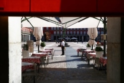 A waiter wearing a protective face mask waits for customers in his terrace at Plaza Mayor square amid the outbreak of the coronavirus disease, in Madrid, Spain, Oct. 1, 2020.