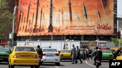 Sebuah billboard menggambarkan rudal balistik Iran dengan teks dalam bahasa Arab yang berbunyi "janji orang jujur" di pusat Tehran, 15 April 2024. Presiden Prancis Emmanuel Macron berusaha keras untuk menghindari eskalasi situasi antara Israel dan Iran. (Foto: AFP)