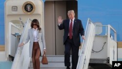 U.S. President Donald Trump, right, waves as he and first lady Melania Trump arrive at the airport in Helsinki, Finland, July 15, 2018, on the eve of his meeting with Russian President Vladimir Putin.