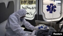 
Seorang anggota staf medis darurat yang mengenakan pakaian pelindung, duduk di ambulans saat memindahkan pasien Covid-19 ke Rumah Sakit Masih Daneshvari, di Teheran, Iran, 30 Maret 2020. (Foto: West Asia News Agency via Reuters)
