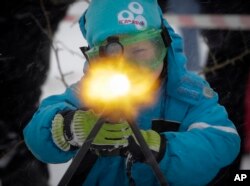 FILE - A boy to shoots a machine gun with blanks, at a weapon exhibition during a military show outside St.Petersburg, Russia, Jan. 15, 2017.