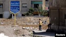 A boy stands near the entrance of the Waer district in the central Syrian city of Homs, Syria, Sept. 19, 2016. 