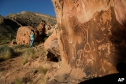In this May 26, 2017, photo, Susie Gelbart walks near petroglyphs at the Gold Butte National Monument near Bunkerville, Nev. The monument is along the Arizona border in Southern Nevada.