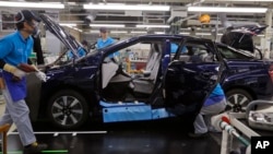 In this Oct. 30, 2017, photo, workers of a Toyota Motor Corp. assemble a Mirai fuel cell vehicle at the automaker's Motomachi plant in Toyota, western Japan. (AP Photo/Yuri Kageyama)