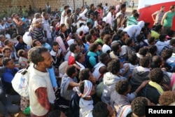 FILE- Migrants are seen after they were relocated from government-run detention centers, after getting trapped by clashes between rival groups in Tripoli, Libya, Sept. 4, 2018.