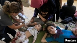 FILE - Wounded and displaced Iraqi children who fled from clashes receive treatment in western Mosul, Iraq, June 3, 2017.