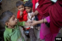 کراچی کی ایک مضافاتی آبادی میں ایک پولیو ورکر بچوں کو ویکیسن کے قطرے پلانے کے بعد نسان لگا رہی ہے۔ فائل فوٹو