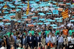 Catalan President Carles Puigdemont, front raw, center, takes part at a march to protest against the National Court's decision to imprison civil society leaders, in Barcelona, Spain, Saturday, Oct. 21, 2017.