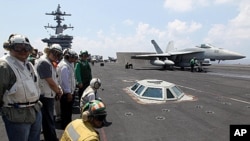 Philippine President Benigno Aquino III (2nd L) watches an F/A-18 Hornet fighter jet about to be catapulted from the US Navy's USS Carl Vinson aircraft carrier near the Philippines, May 14, 2011