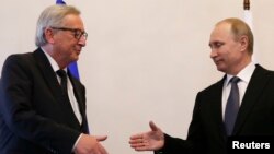 Russian President Vladimir Putin, right, approaches to shake hands with European Commission President Jean-Claude Juncker during a meeting in St. Petersburg, Russia, June 16, 2016. 