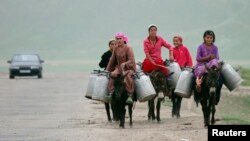 FILE - Women ride donkeys loaded with water canisters outside the Central Asian village of Gargara, 110 kilometers (68 miles) south of Dushanbe, Tajikistan, May 4, 2008. 