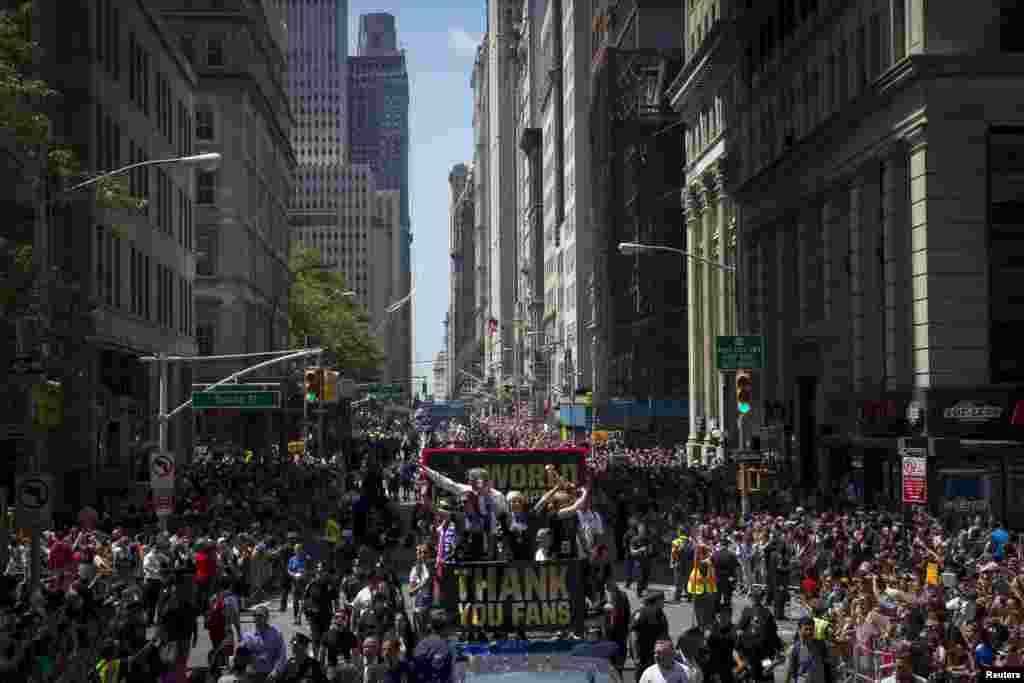 U.S. women's soccer player Megan Rapinoe (C) holds the Wold Cup trophy as she rides a float with teammate Carli Lloyd (L) and New York Mayor Bill de Blasio during the ticker tape parade up Broadway in lower Manhattan to celebrate their World Cup final win