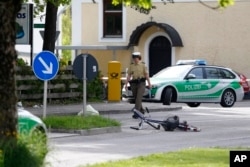 Police officers pass by a restaurant outside the station in Grafing near Munich, Germany, Tuesday, May 10, 2016.
