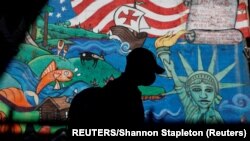 Seorang pria mengenakan masker berjalan melewati sebuah mural, di wilayah Queens di New York, AS, di tengah pandemi COVID-19, 8 September 2020. (Foto: dok). 