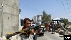 A Taliban fighter holds a rocket-propelled granade launcher as he stands guard with others at an entrance gate outside the Interior Ministry in Kabul, Afghanistan, Aug. 17, 2021. 