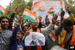 Indians wave national flags as they wait for the release of an Indian air force pilot by Pakistani authorities, in Jammu, India, March 1, 2019.