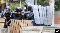 A Nicaraguan police officer aims his weapon at protesting students during a third day of violent clashes in Managua, Nicaragua, April 20, 2018.
