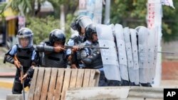 Pasukan keamanan mengarahkan senjatanya ke arah para demonstran mahasiswa dalam protes yang rusuh di Managua, Nikaragua (20/4).