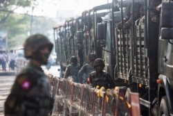 FILE - Soldiers stand next to military vehicles in Yangon, Myanmar, February 15, 2021.