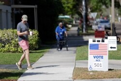 FILE - A young voter, left, leaves a polling station after casting his ballot in Florida's primary election, in Orlando, Florida, March 17, 2020.