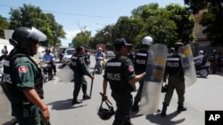 Cambodian riot police officers walk towards workers gathering in front of National Assembly in Phnom Penh, Cambodia, Tuesday, June 30, 2015.