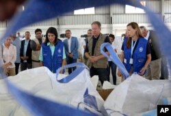 U.S. Ambassador to the United Nations Nikki Haley, center left, and World Food Program director David Beasely, center inspects a food pallet to be air-dropped deep inside Syria, in Amman, Jordan, May 21, 2017.