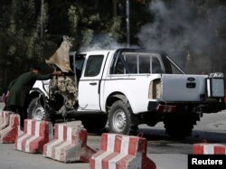 An Afghan plainclothes policeman inspects a military vehicle that was hit by a magnetic bomb in Kabul, Sept. 28, 2014.