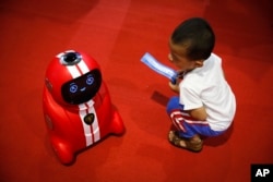 A child holding an entrance ticket watches a smart self-learning robot during the World Robot Conference at the Yichuang International Conference and Exhibition Centre in Beijing, Aug. 23, 2017.
