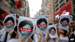 Protesters hold pictures of Hong Kong Chief Executive Carrie Lam as protesters march along a downtown street against the proposed amendments to an extradition law in Hong Kong Sunday, June 9, 2019.19.