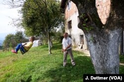 Huso Ahmić, 72, plays with his grandson in the garden of the family home that was razed during a Croatian “ethnic cleansing” assault on the villages of the Lašva Valley in 1993.