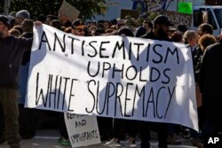 FILE - Protesters hold a sign on the block of the Jewish Community Center in the Squirrel Hill neighborhood of Pittsburgh, Oct. 30, 2018.