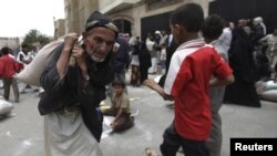 FILE - A man carries food aid provided by the Red Crescent Society in Sana'a.