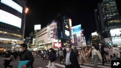 Pedestrians wear face masks in hopes of preventing the spread of the coronavirus walk through a crossing in the Shibuya district in Tokyo, March 16, 2020. 