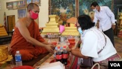 រូប​ឯកសារ៖ ស្រ្តី​ម្នាក់​កំពុង​ប្រគេន​ទេយ្យទាន​ដល់​ព្រះ​សង្ឃ​​ក្នុង​វត្ត​និរោធ​រង្សី រាជធានី​ភ្នំពេញ ក្នុង​អំឡុង​​ពេល​​ប្រារព្ធ​ពិធី​បុណ្យ​ចូល​ឆ្នាំ​ខ្មែរ​ថ្ងៃទី​២ នៅ​ថ្ងៃ​ទី​១៤ ខែមេសា ឆ្នាំ​២០២០។ (កាន់ វិច្ឆិកា/VOA)​​