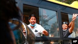 An arrested protester flashes the three-fingered salute while aboard a bus getting out of Insein prison to go to an undisclosed location, March 24, 2021, in Yangon, Myanmar. 