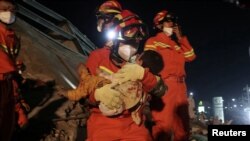 7일 붕괴된 중국 푸젠성 신자 호텔에서 구조대원이 어린 아이를 구출해 나오고 있다.