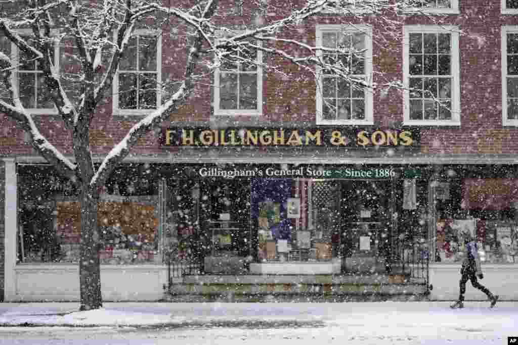 A walker passes by a store during a Thanksgiving Day snowstorm on November 28, 2024, in Woodstock, Vermont.
