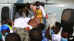 FILE - Health workers carry a wounded Tanzanian from a military helicopter at Jangwani grounds in Dar es Salaam, Tanzania, Aug. 11, 2019. 