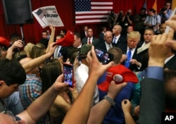 FILE - Supporters wave signs as Republican presidential candidate Donald Trump, center right, signs autographs for supporters after speaking at a campaign event on May 19, 2016, in Lawrenceville, N.J.